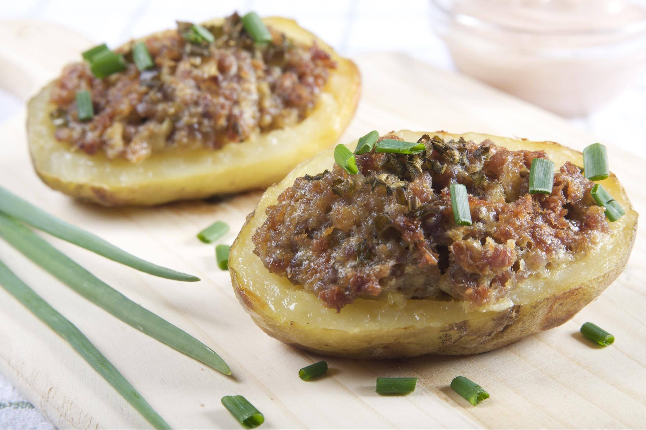 Su un bancone piastrellato nero vengono offerte porzioni di patatine fritte  con sopra formaggio e carne macinata di manzo t