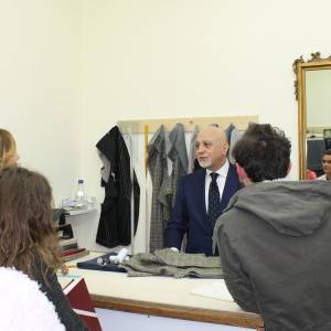 Il maestro di stile si intrattiene con alcuni clienti all’interno dell’atelier di via Dei Mille